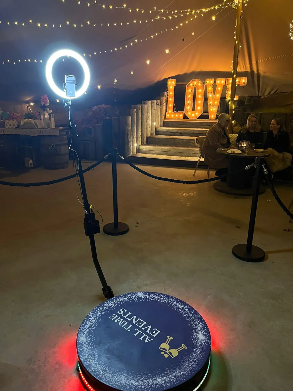 All Time Events 360 photo booth with ring light, rope barriers and glowing LOVE letters in a marquee